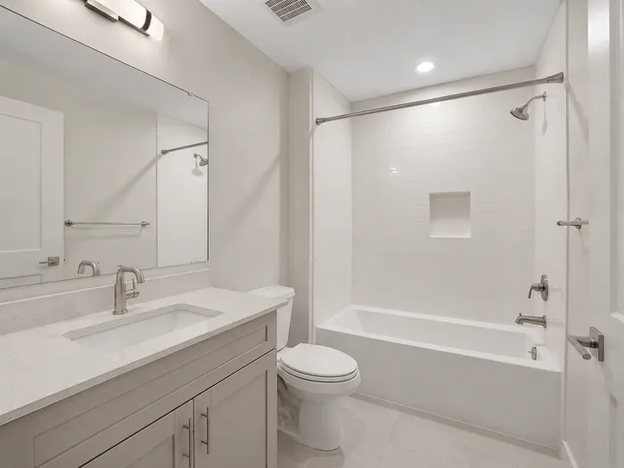 White basement bathroom with tub shower, tile niche, and greige vanity