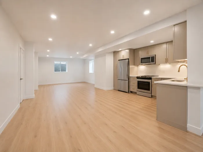 Wide basement family room with recessed lighting flowing into the kitchen area