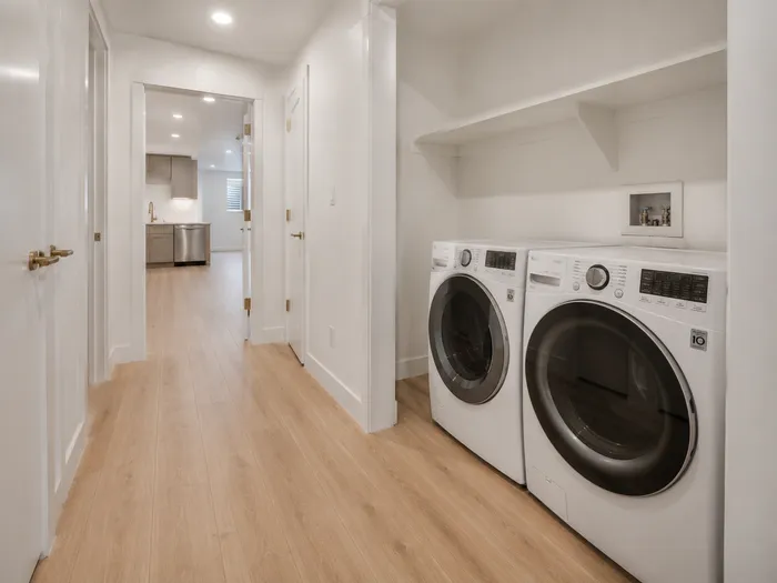Basement hallway with laundry nook, front-load washer and dryer, and built-in shelf